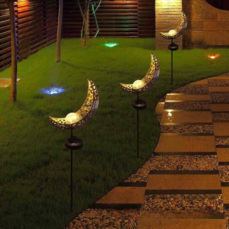 Decorative outdoor lights shaped like moons on stakes in a garden setting.