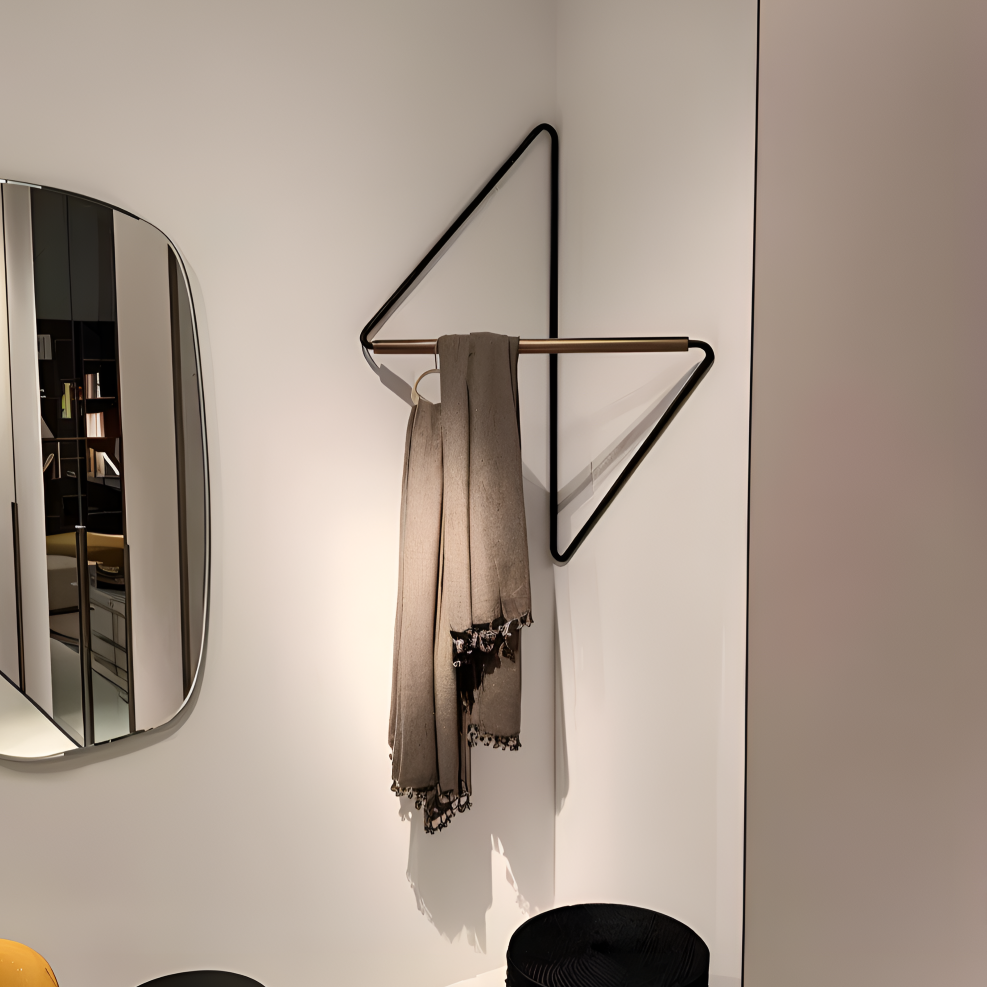 Modern wall hook with a scarf hanging on a white wall next to a mirror.