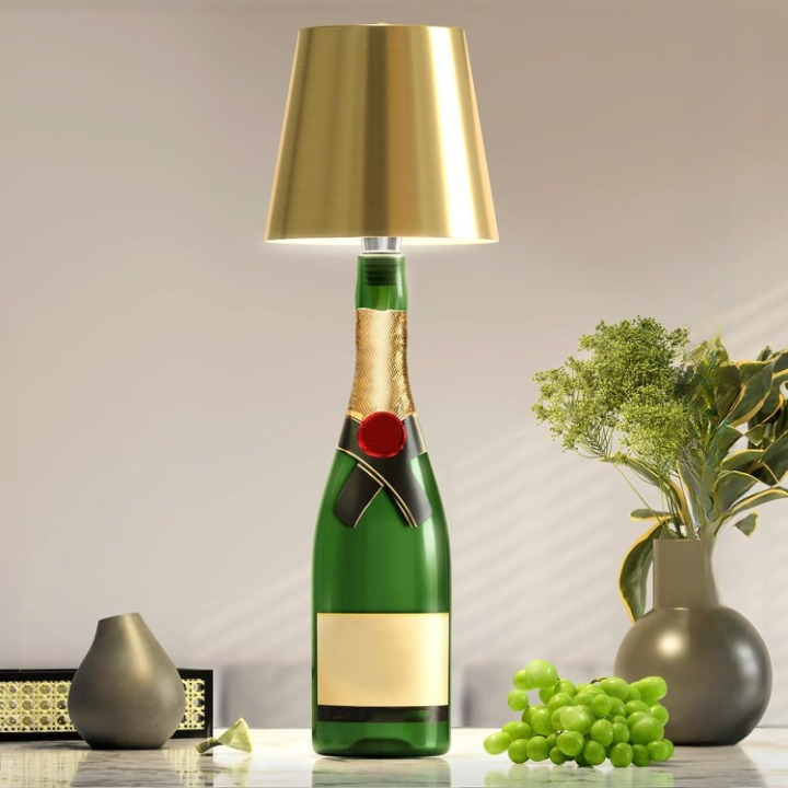 Champagne bottle lamp with gold shade on a table with decorative items.