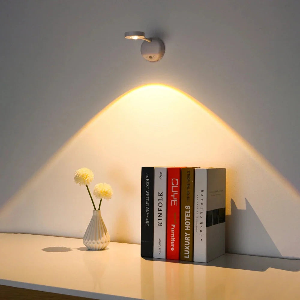 Wall-mounted light fixture casting a warm glow on a shelf with books and a vase.