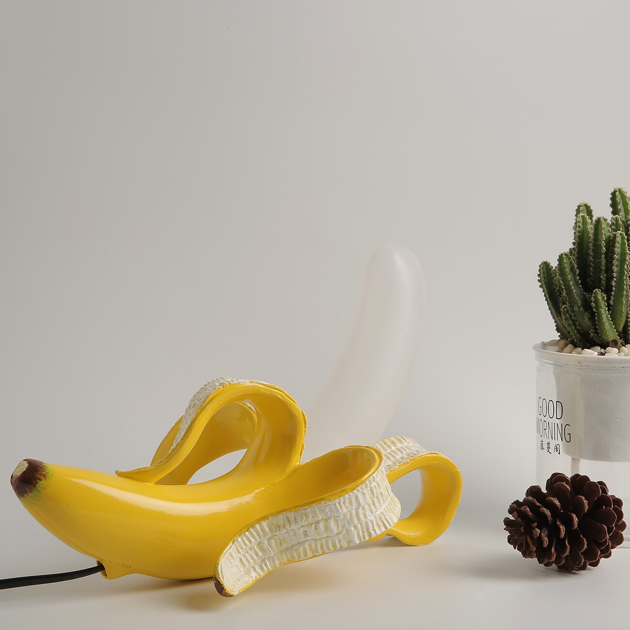 Yellow banana-shaped device on a light surface with a cactus and pine cone in the background.