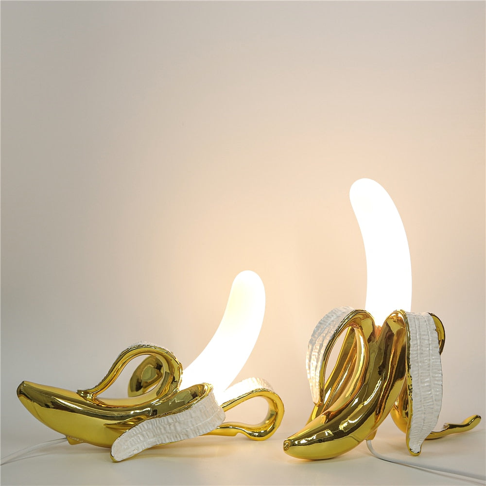 Gold banana-shaped lamps on a white surface with a neutral background
