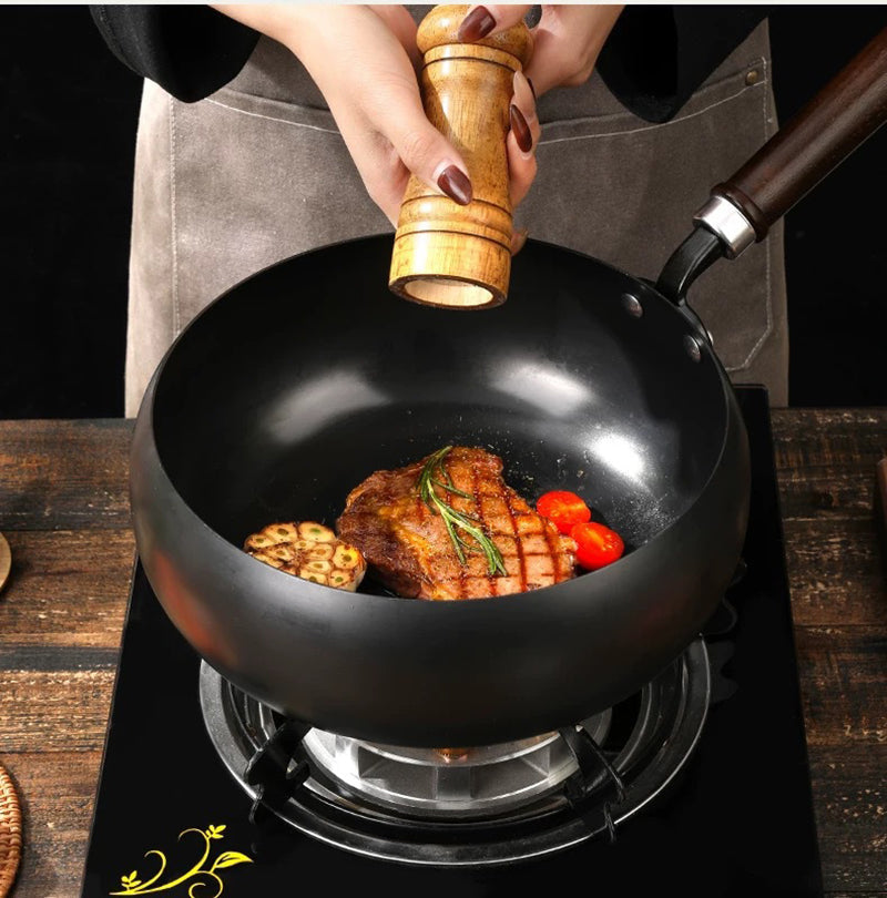 Person seasoning food in a frying pan on a stove