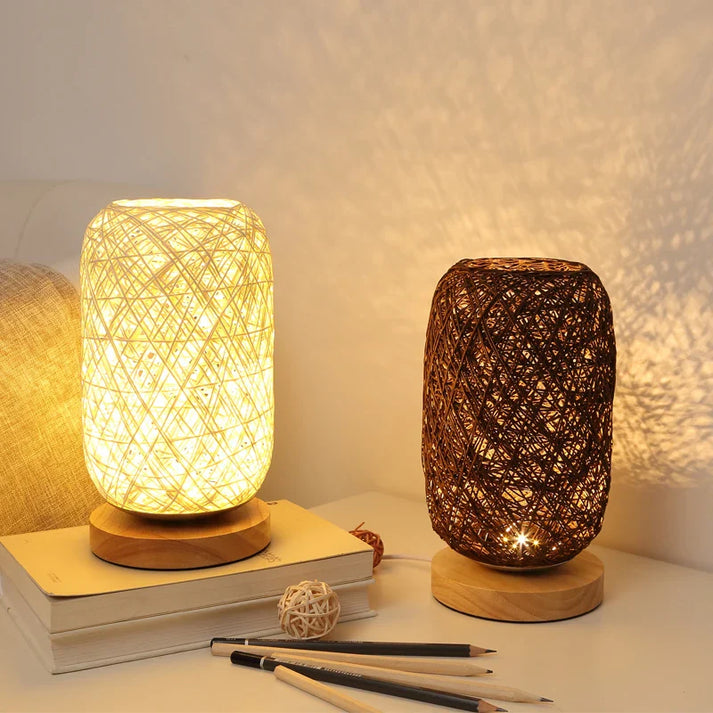 Two woven table lamps on a surface with books and pens.