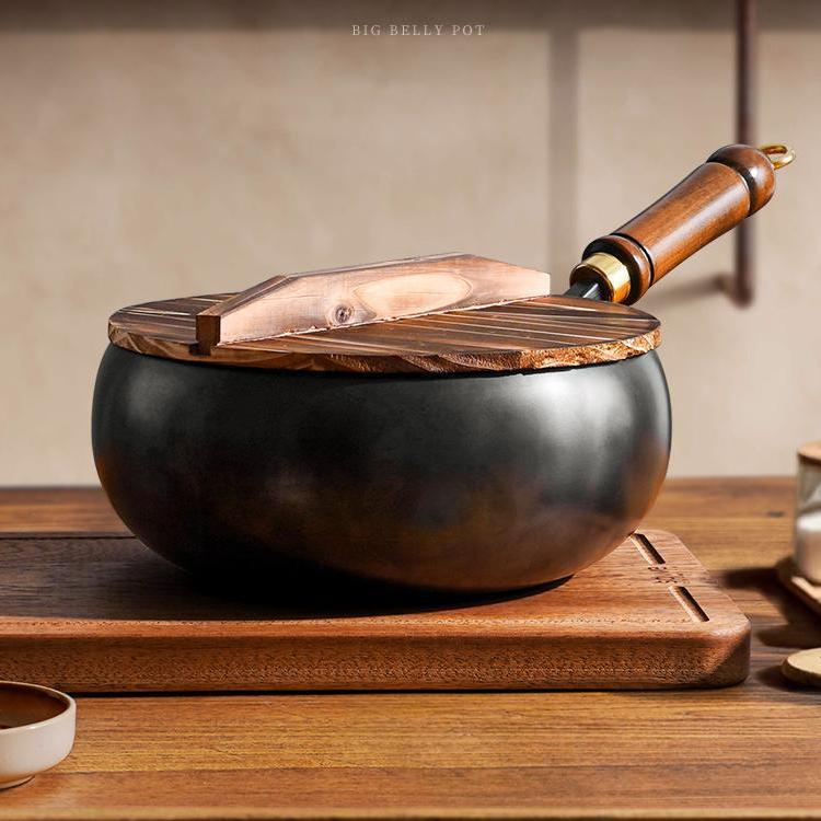 Black pot with wooden lid and handle on a wooden surface