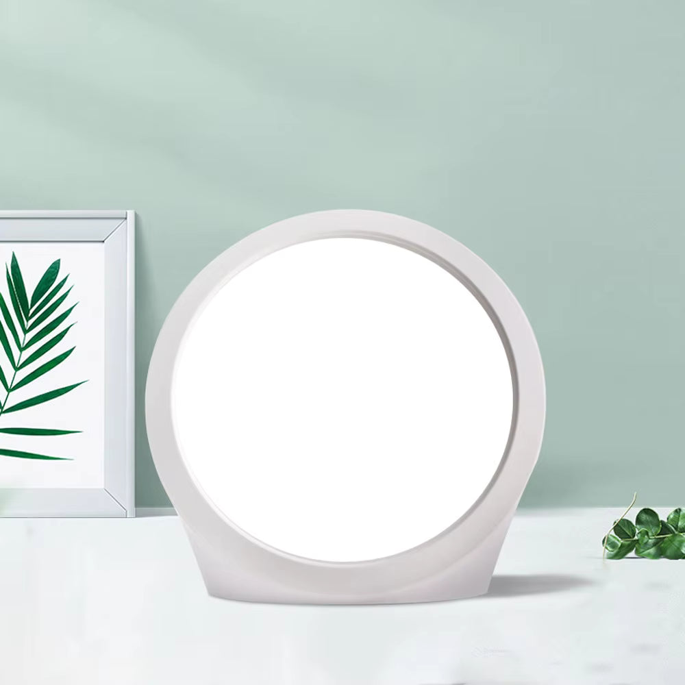 Round white lamp on a light green background with a framed leaf print and eucalyptus leaves.