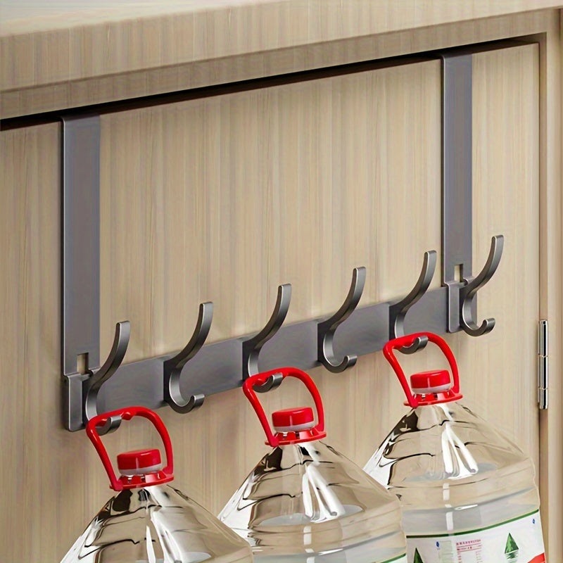 Wall-mounted hook with red handles holding glass bottles against a wooden background