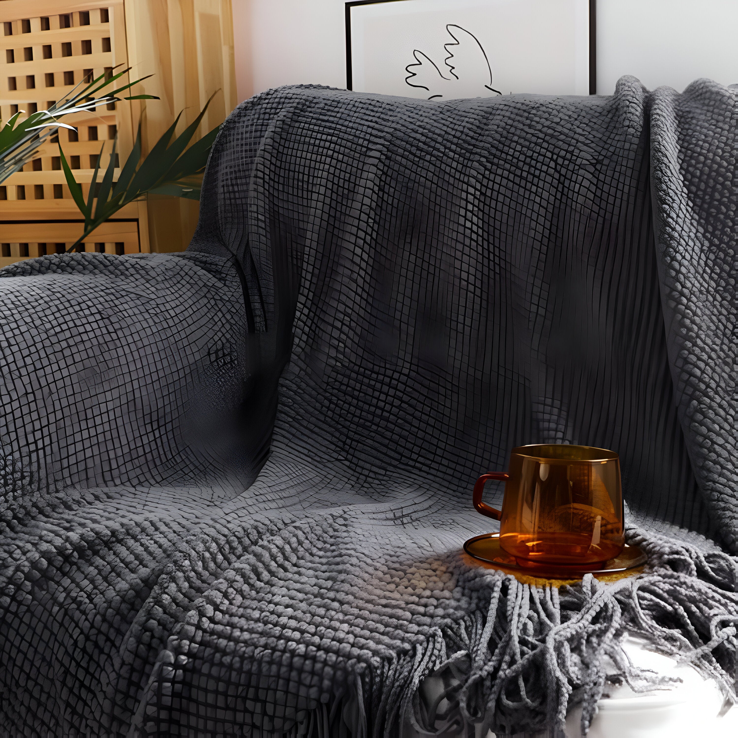 Gray textured blanket draped over a sofa with a brown mug on a small table.