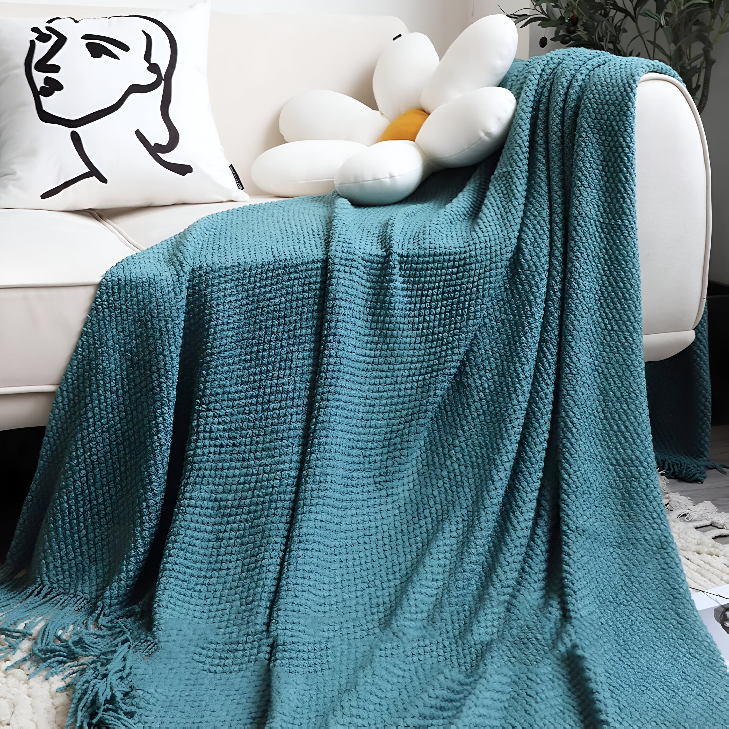 Teal blanket draped over a chair with a white cushion and stuffed toy in the background