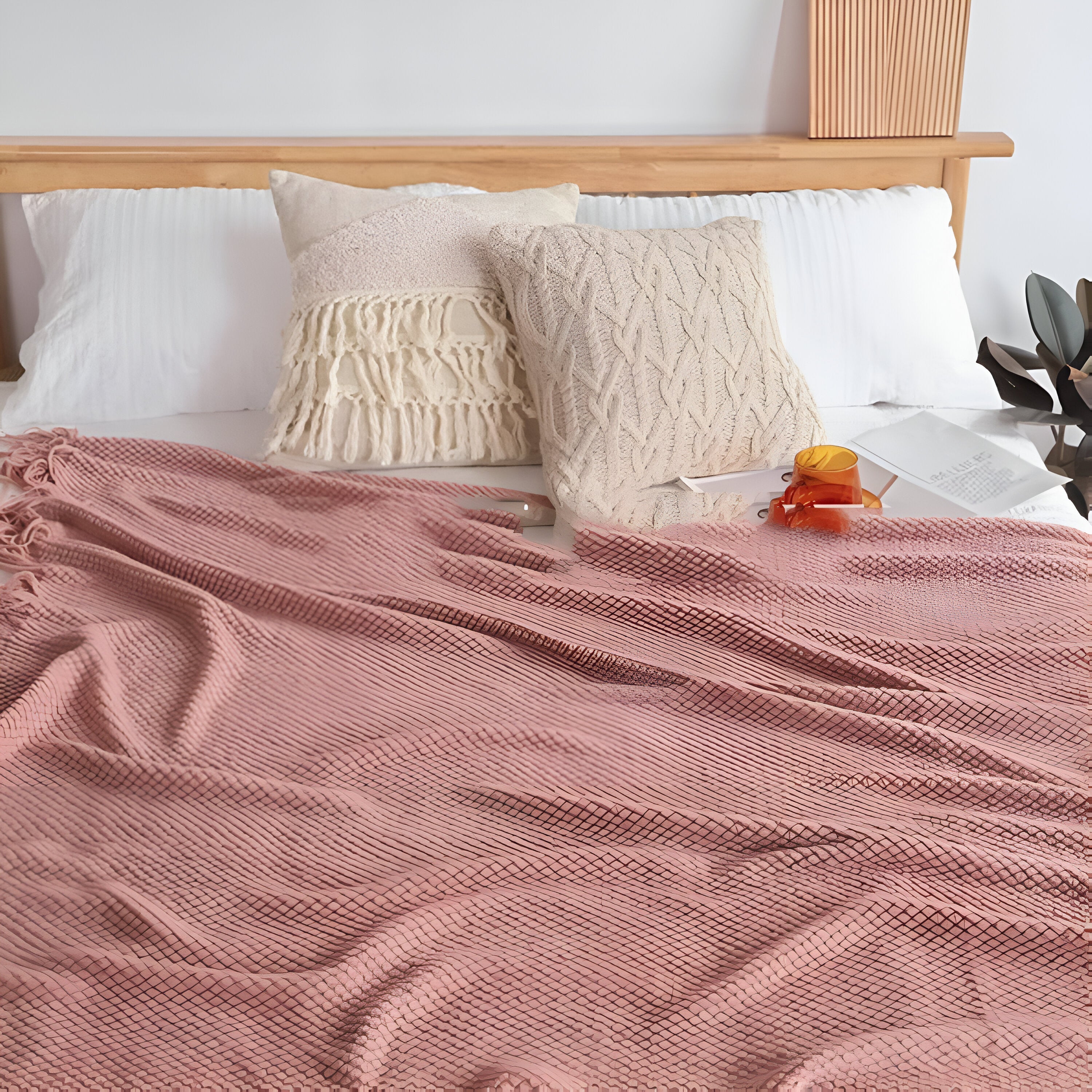 Bed with pink blanket, white pillows, and a wooden headboard.