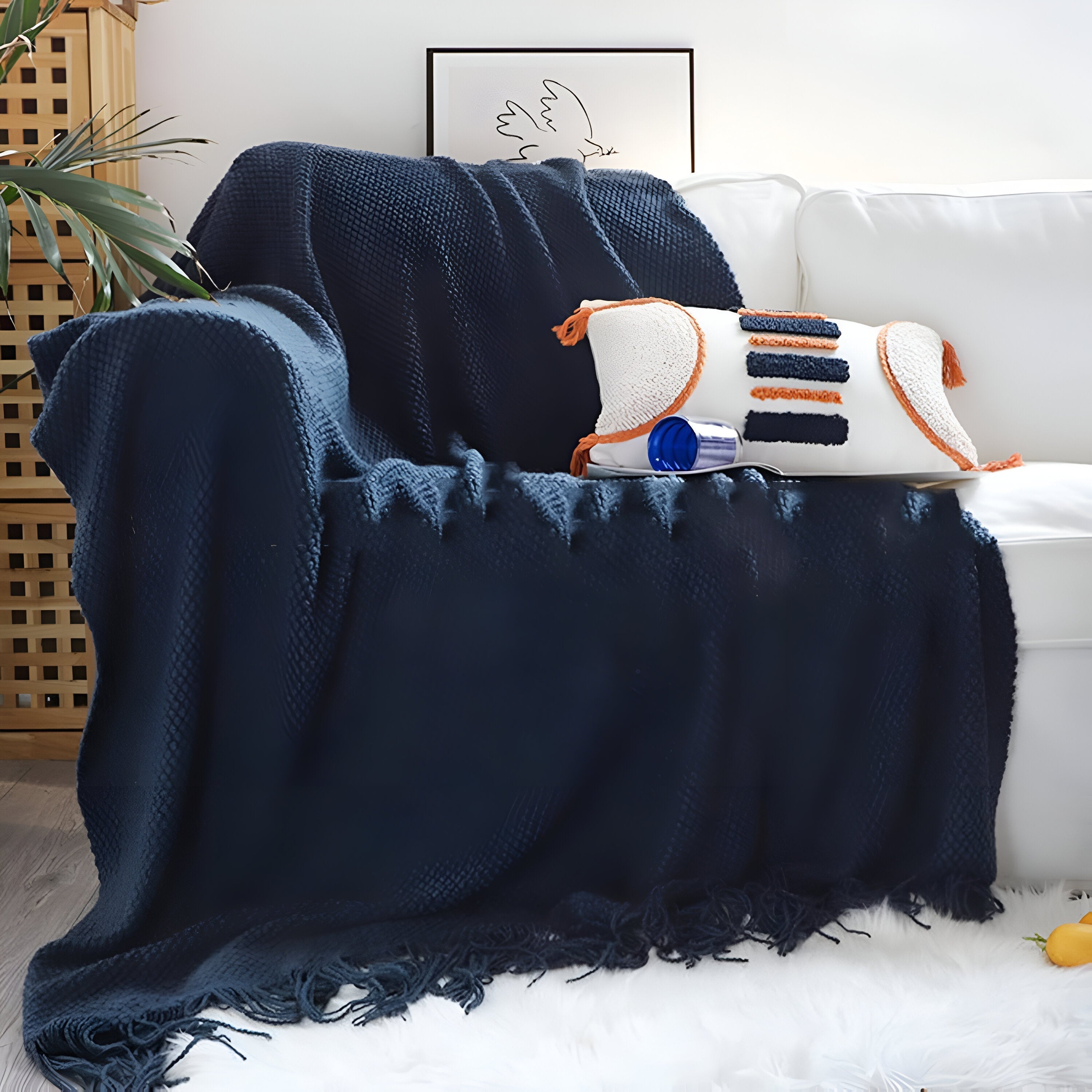 Navy blue blanket draped over a white sofa with a decorative pillow.