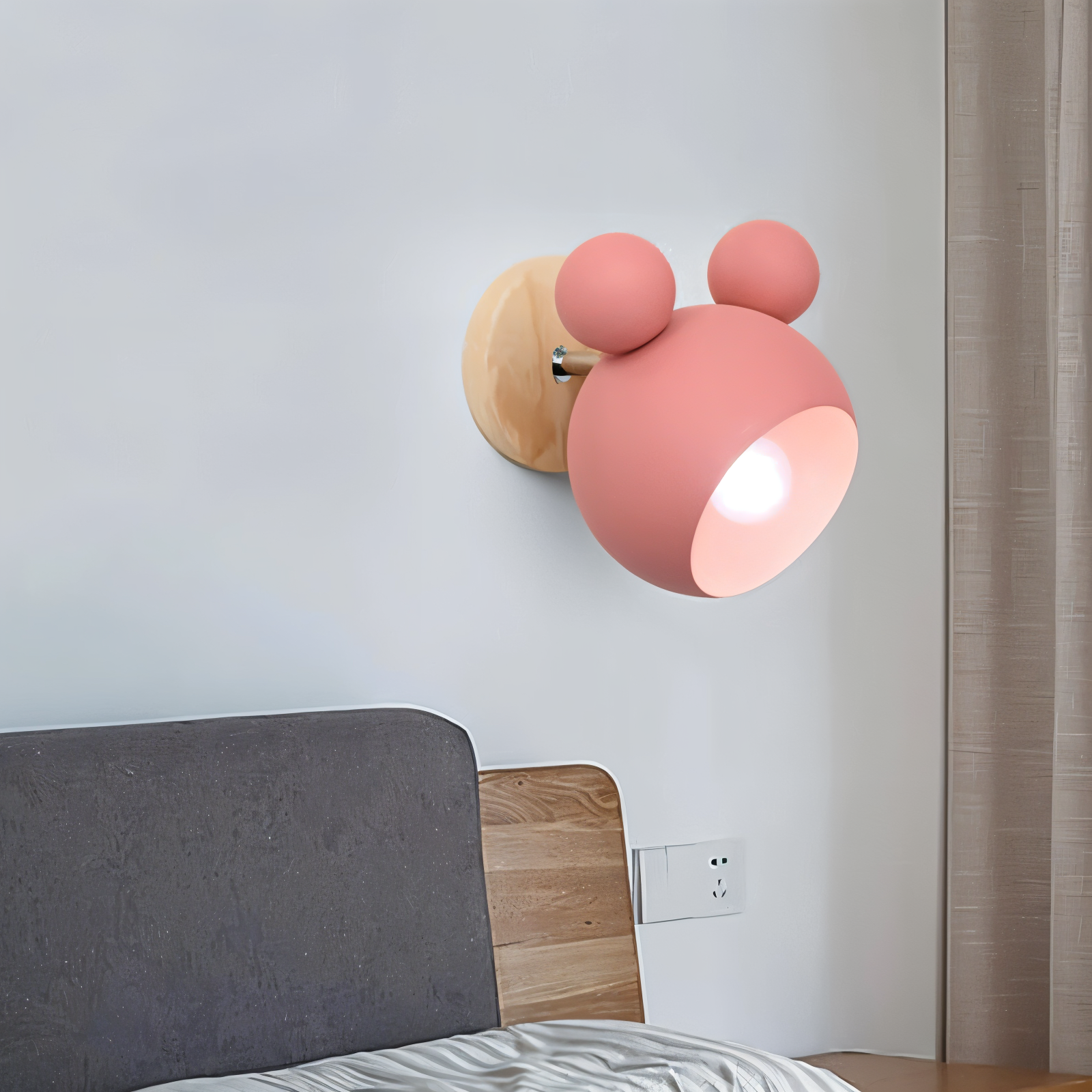 Pink wall lamp with wooden base on a light gray wall above a bed.