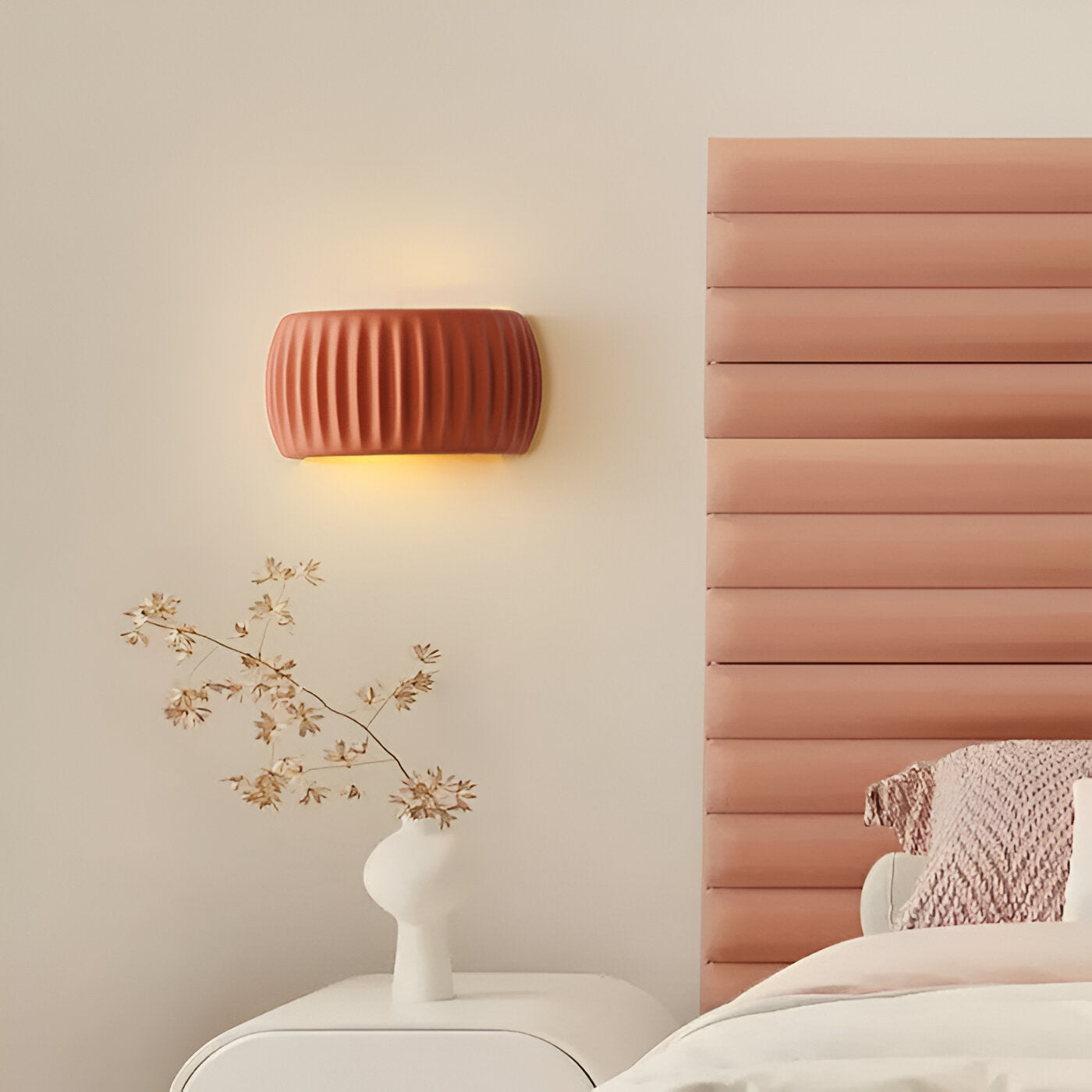 Decorative wall lamp on a beige wall next to a bed with a pink headboard.