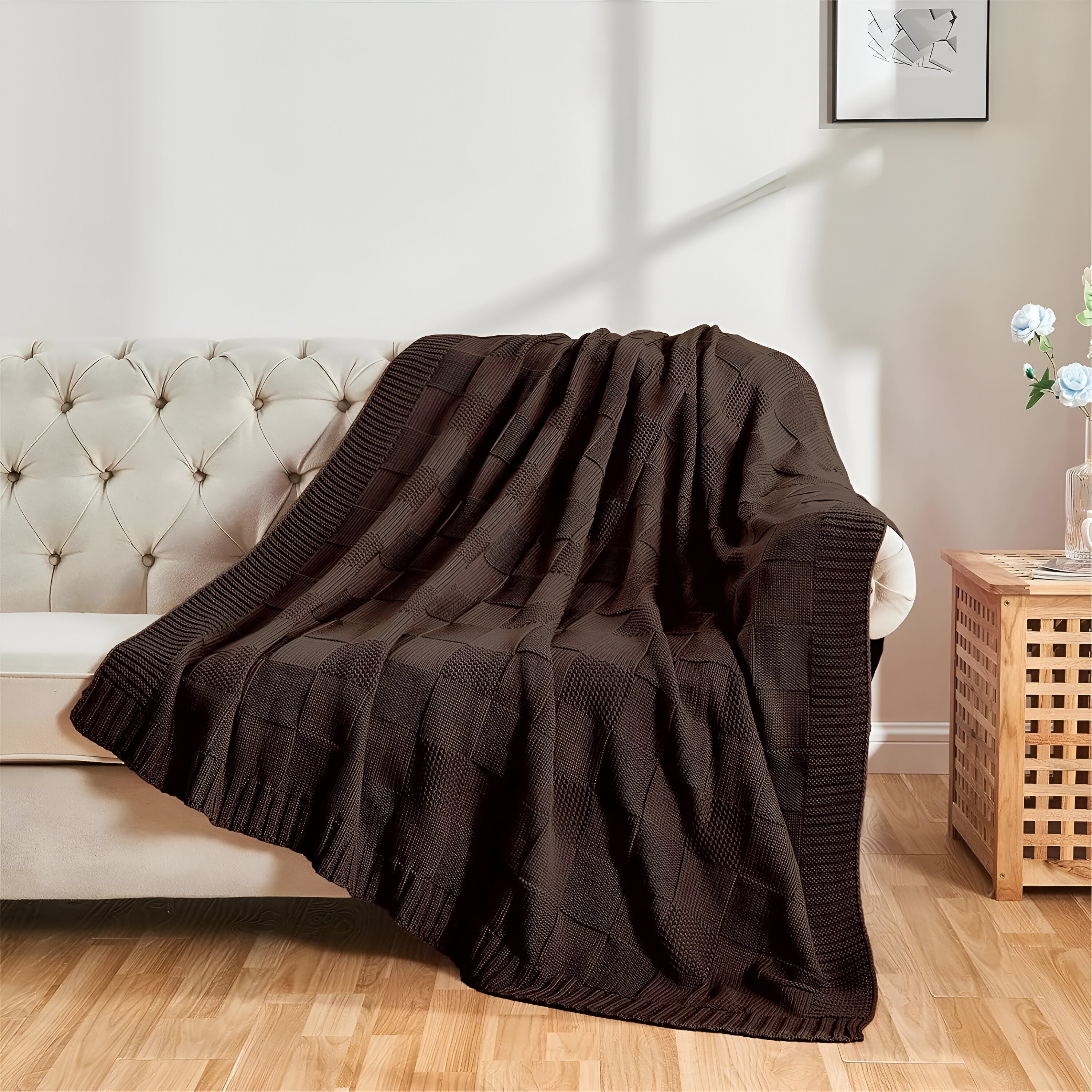Brown knitted blanket draped over a white sofa in a living room setting.