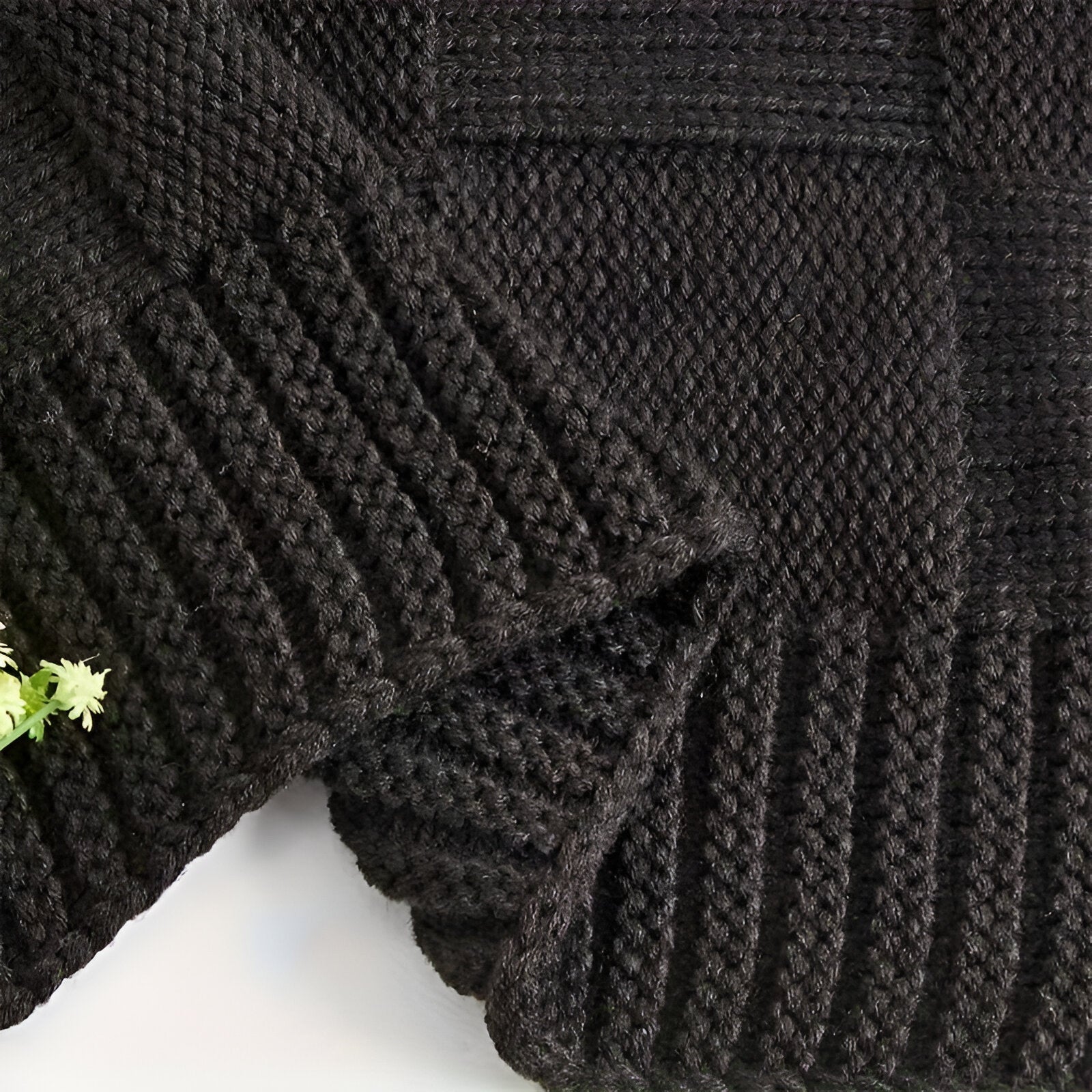 Close-up of a dark gray knitted sweater with a textured pattern on a white background