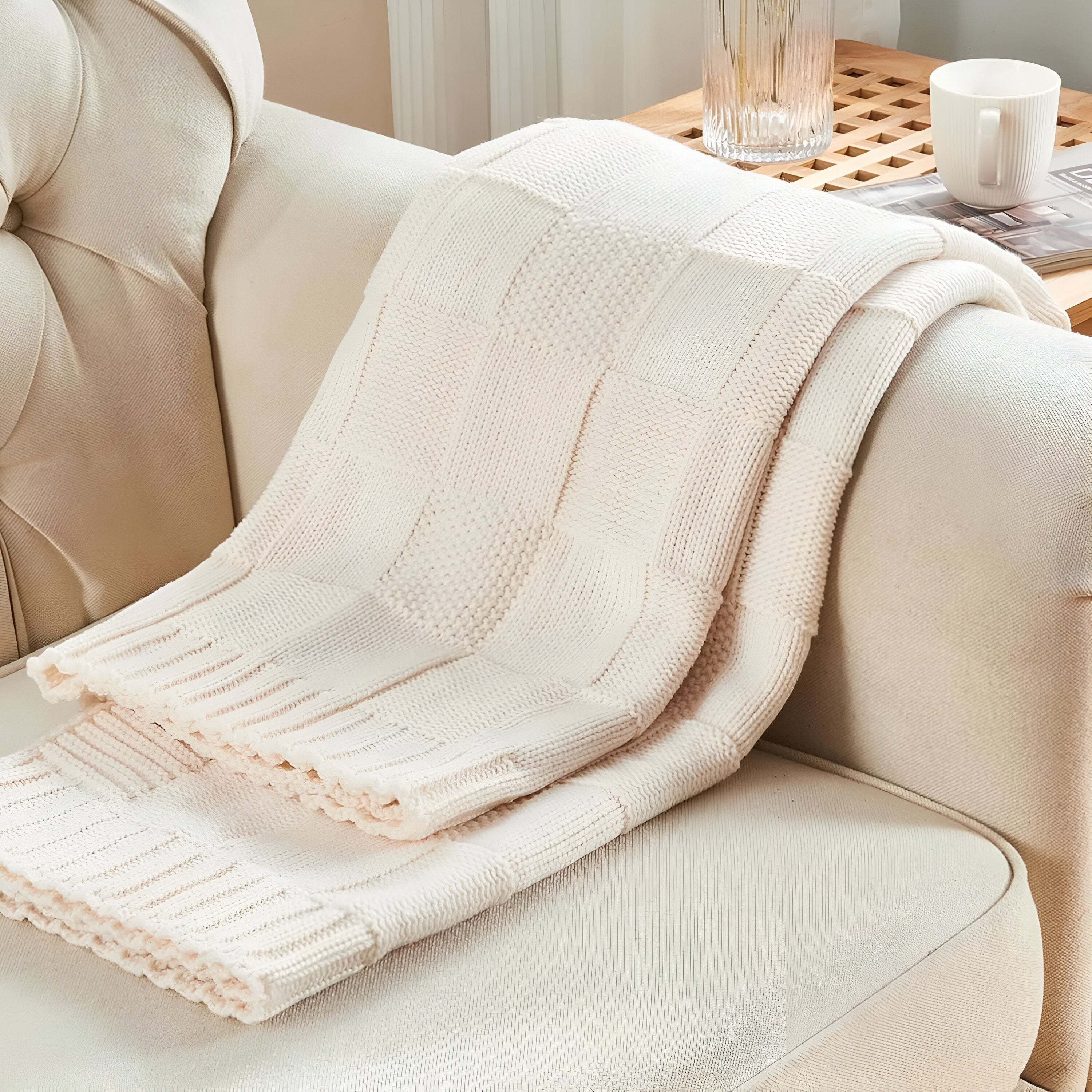 Beige textured blanket draped over a beige armchair with a blurred background