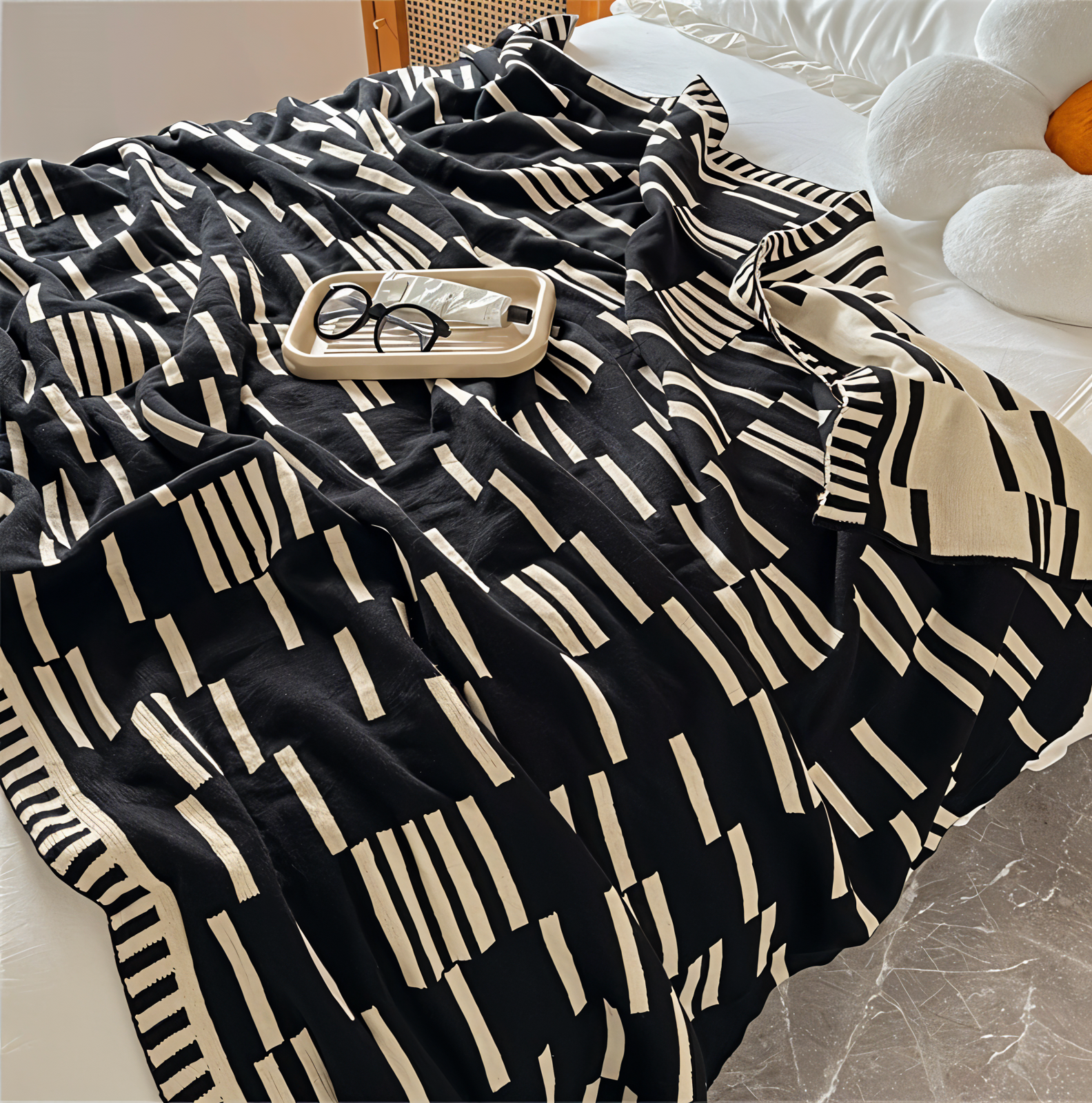 Black and white patterned blanket draped over a surface with a small tray and glasses on top.