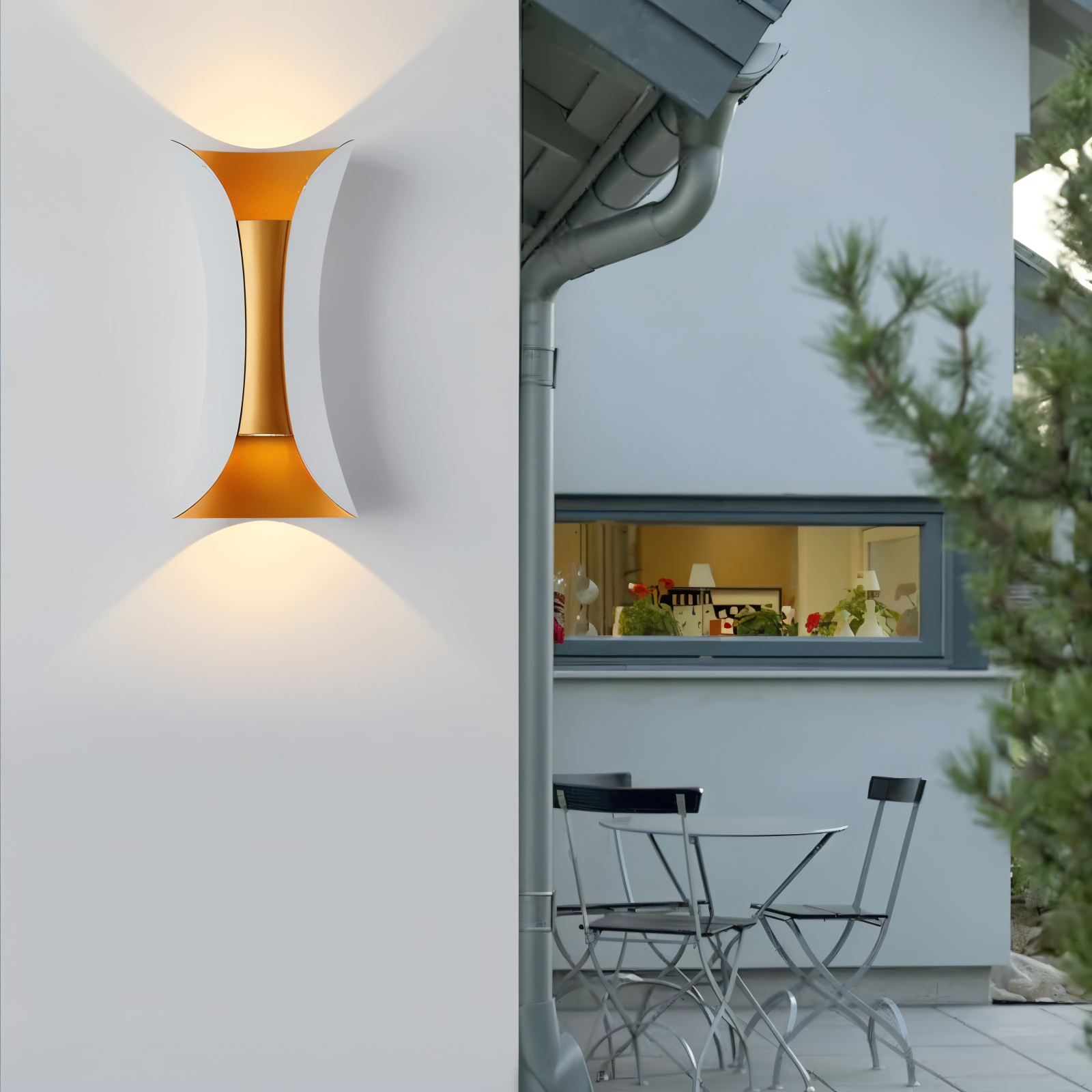 Modern outdoor wall light fixture on a white wall with a view of a patio through a window.