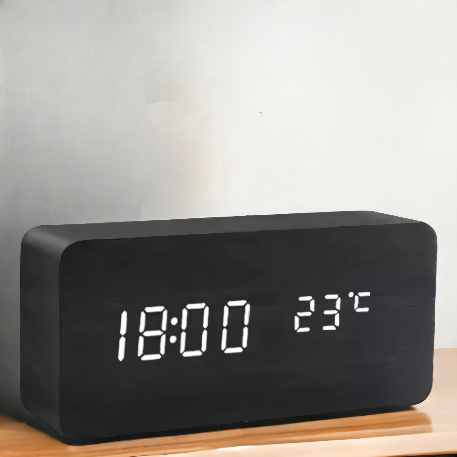 Black digital clock with LED display on a wooden stand