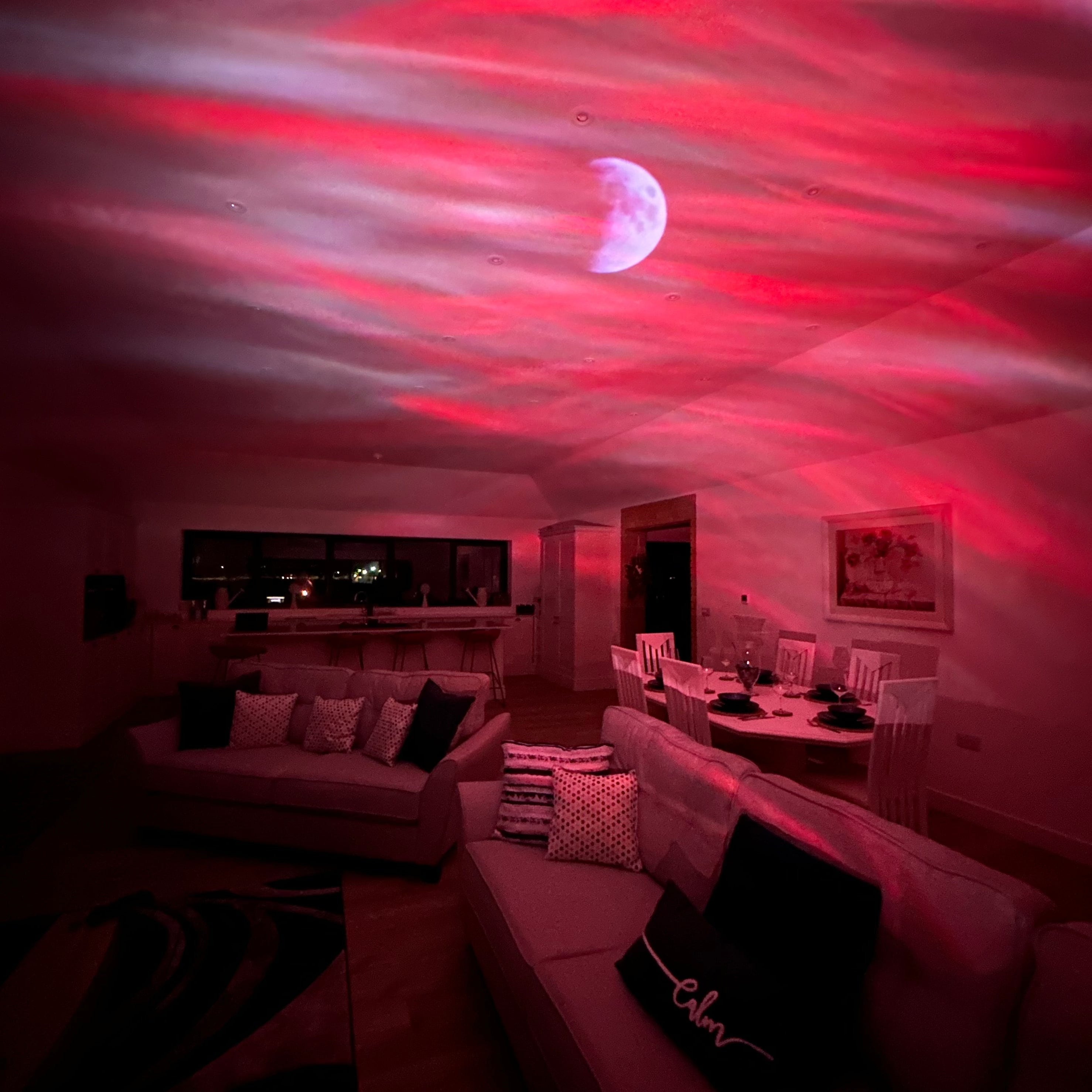 Living room with red lighting projected onto the ceiling, creating a dramatic effect.
