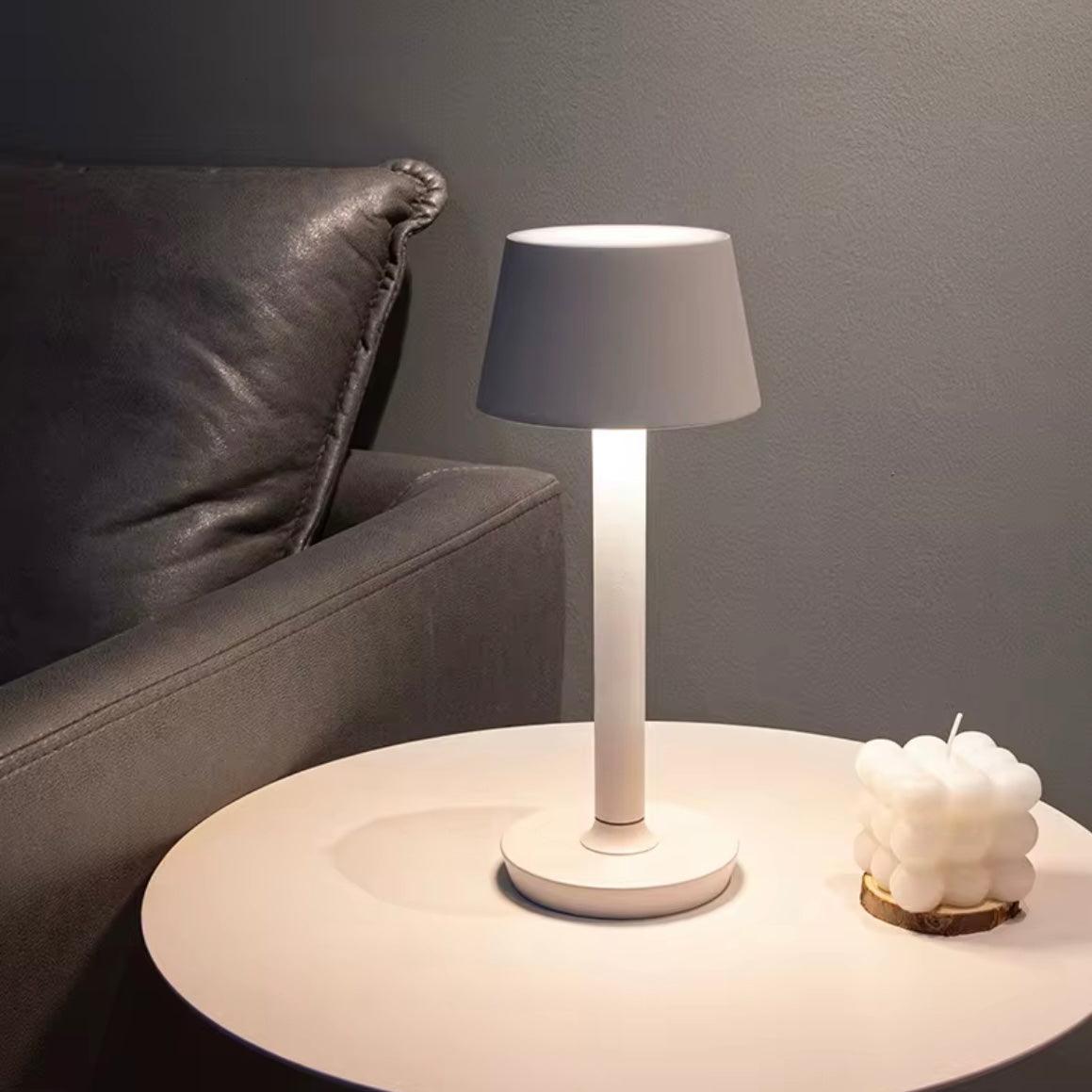 Table lamp on a round side table with a gray sofa and decorative item in the background