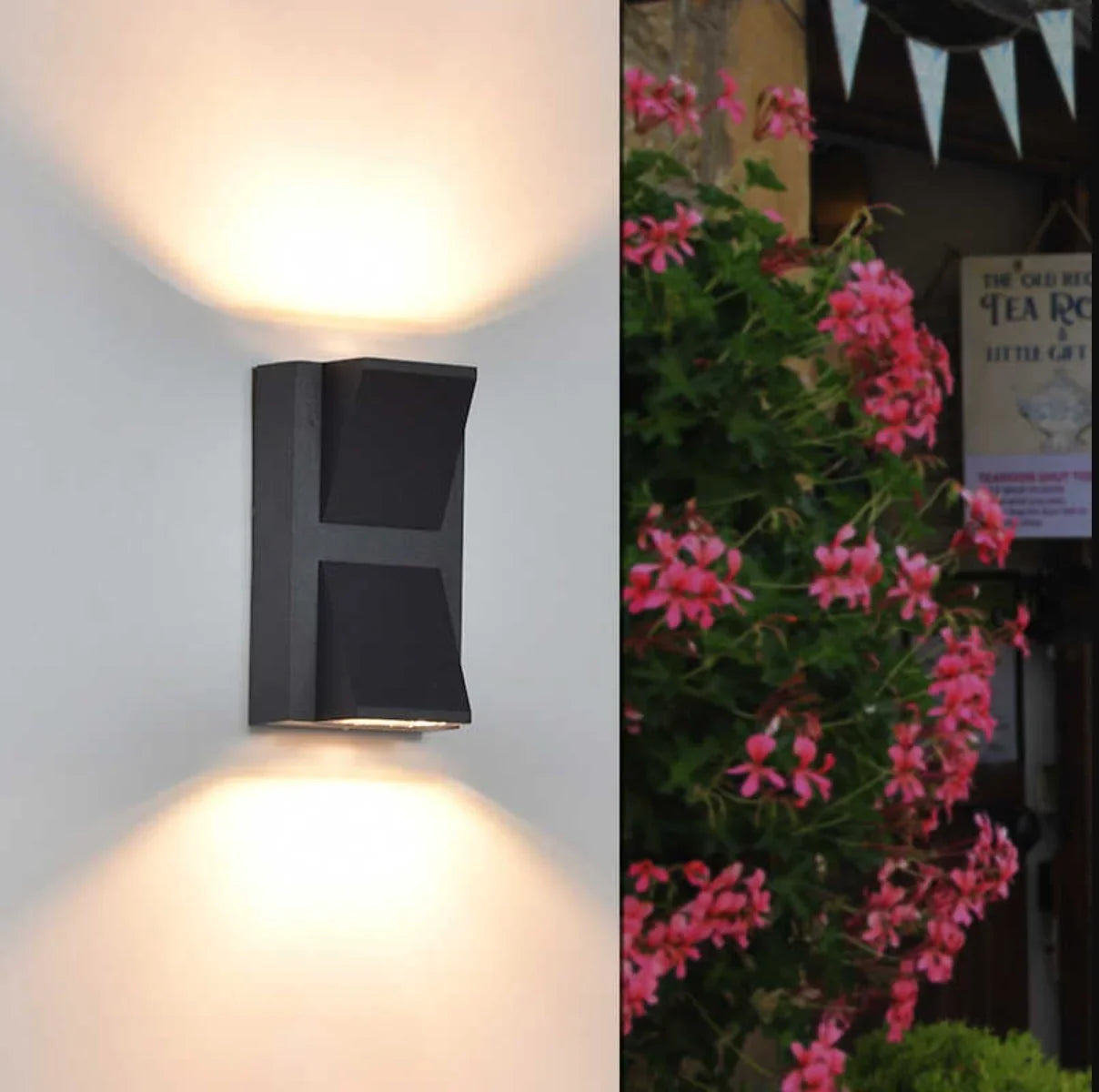Black outdoor wall light fixture on a white wall with pink flowers and a sign in the background.