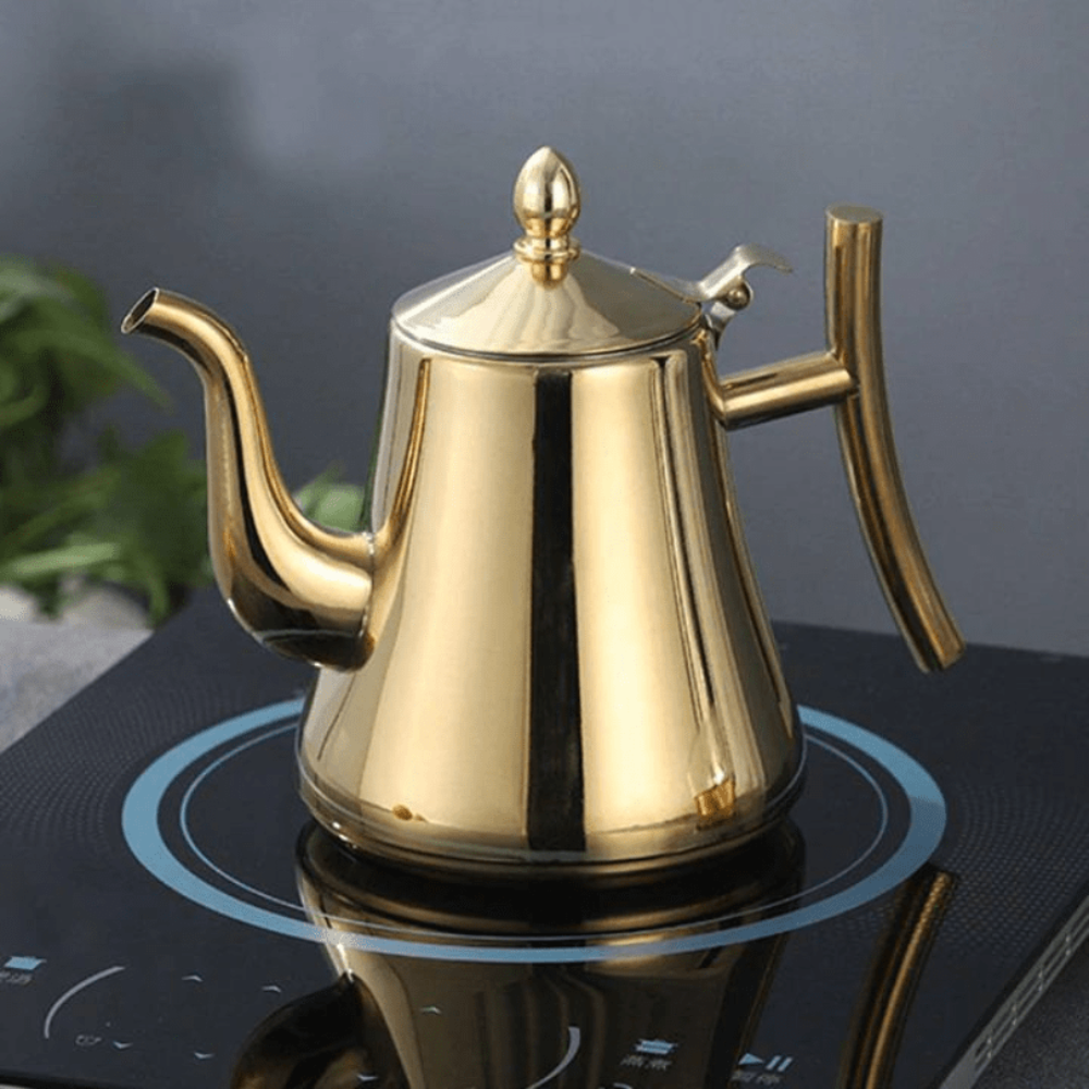 Gold teapot on a black electric stove with a blurred background