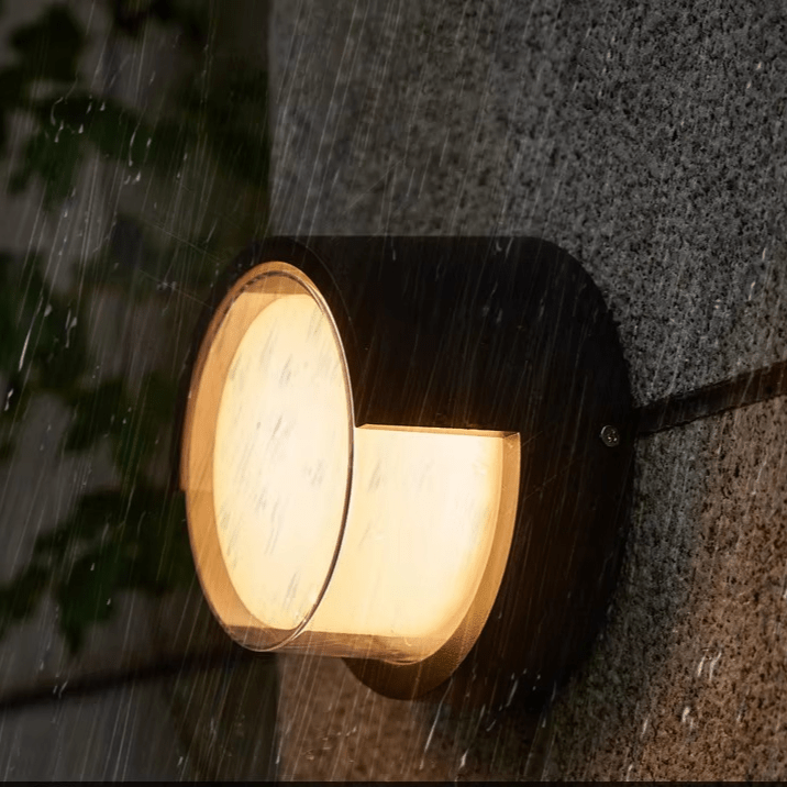 Wall-mounted outdoor light fixture on a textured wall with raindrops.