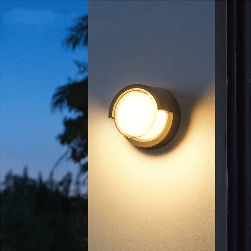 Round outdoor wall light fixture on a building exterior with a dark sky background