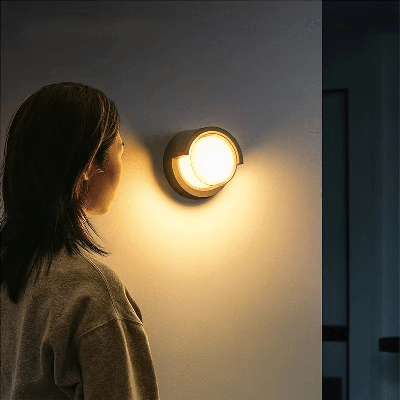 Person looking at a wall-mounted light fixture on a dark wall