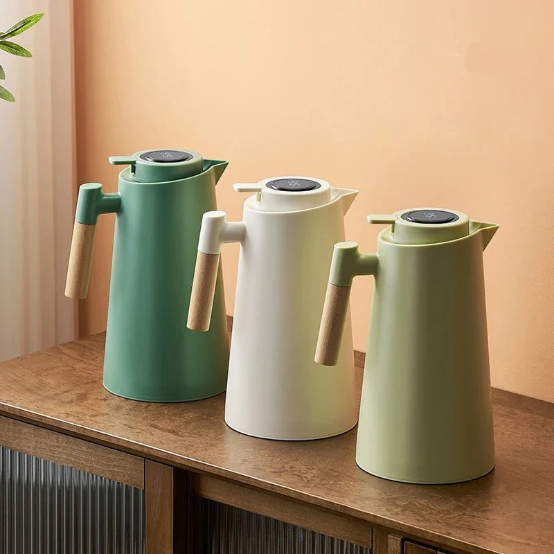 Three green and white thermos bottles with wooden handles on a wooden surface.