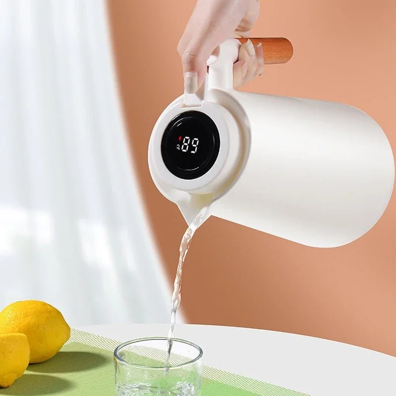 White electric kettle with digital display pouring water into a glass on a light background