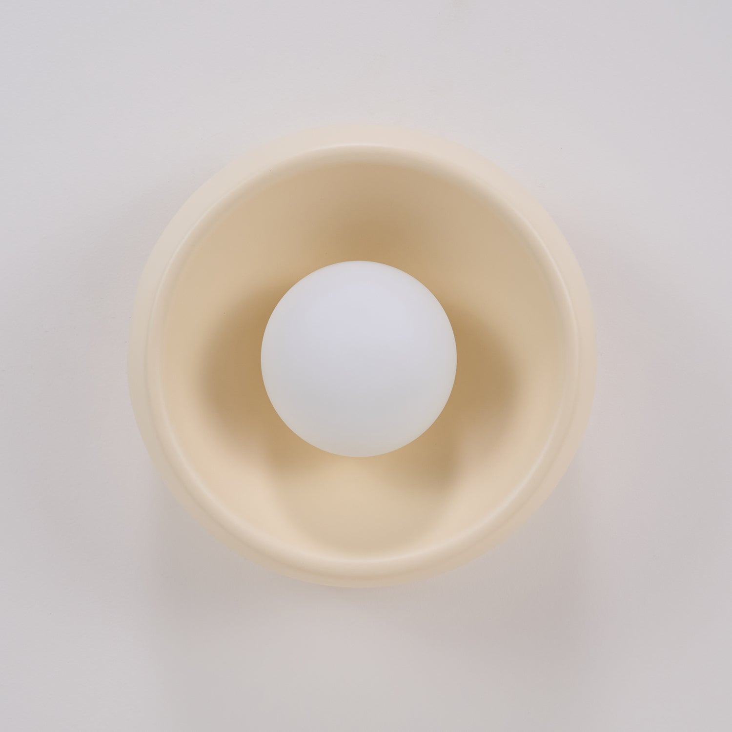White ping pong ball inside a beige bowl on a light gray background