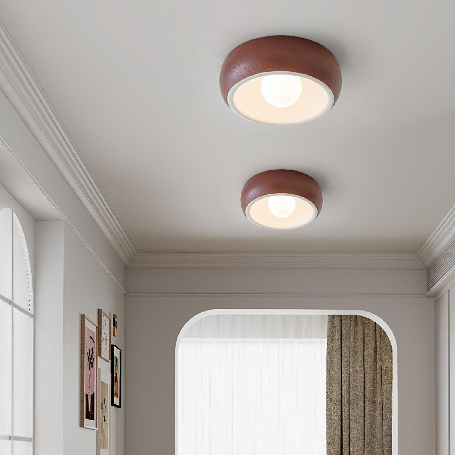 Two round ceiling lights on a white ceiling with a room in the background.