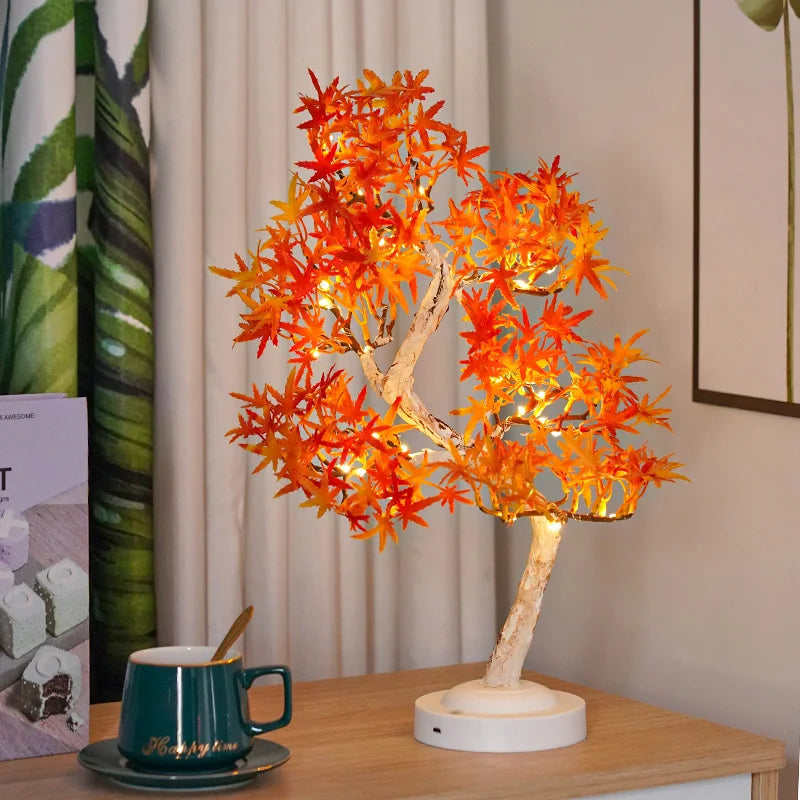 Decorative lamp with orange leaves on a wooden table next to a mug.