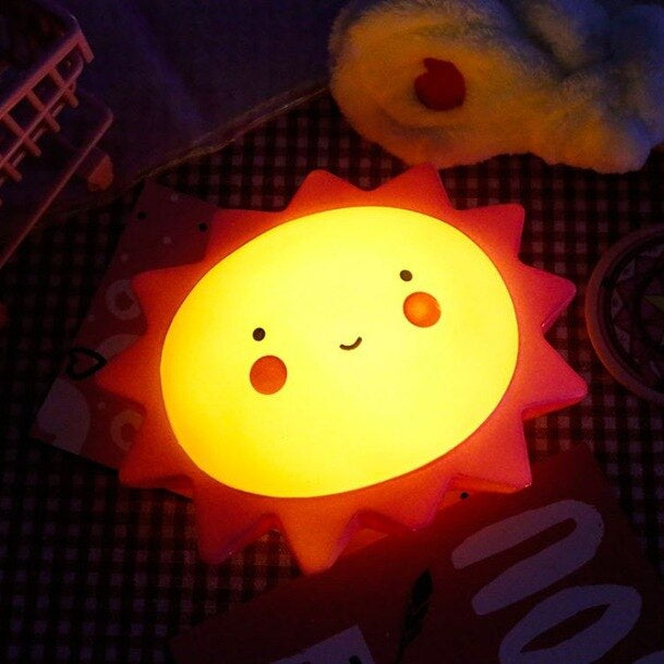 Sun-shaped night light with a smiling face on a dark surface