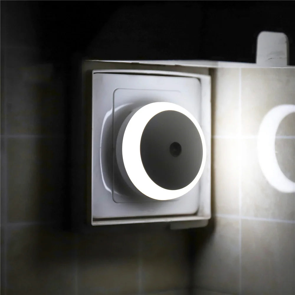 Wall-mounted night light emitting a soft glow on a tiled wall.