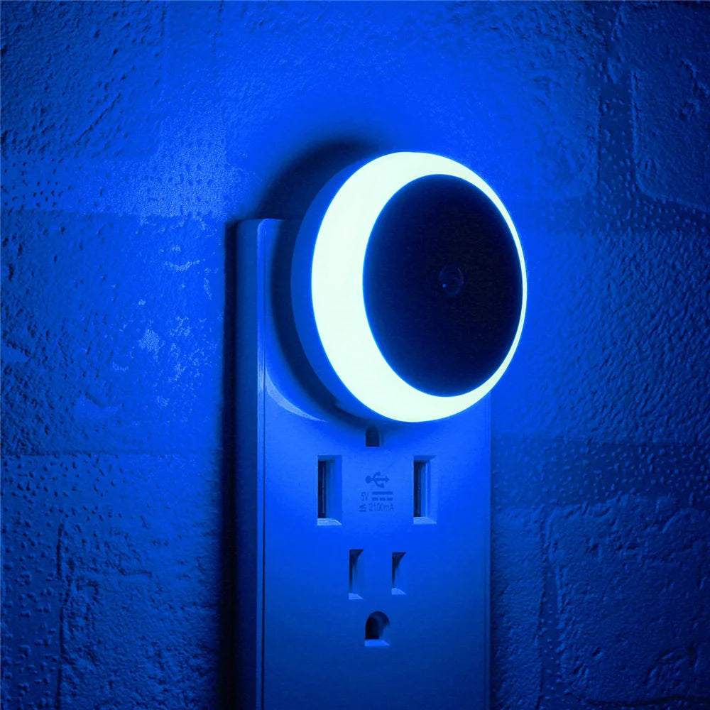 Night light attached to a wall socket with a blue glow on a textured blue wall.