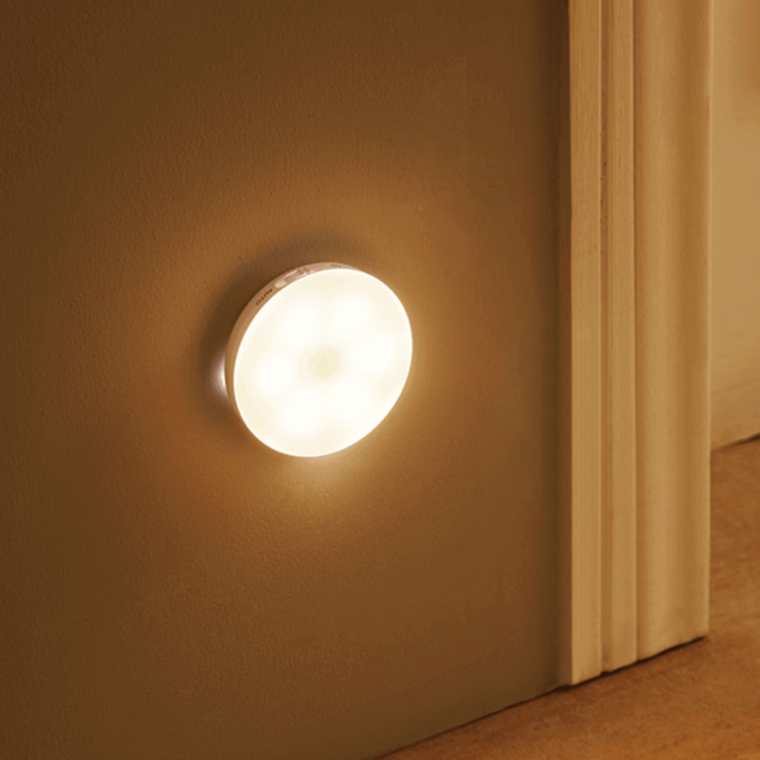 Round wall light fixture on a beige wall next to a wooden door.