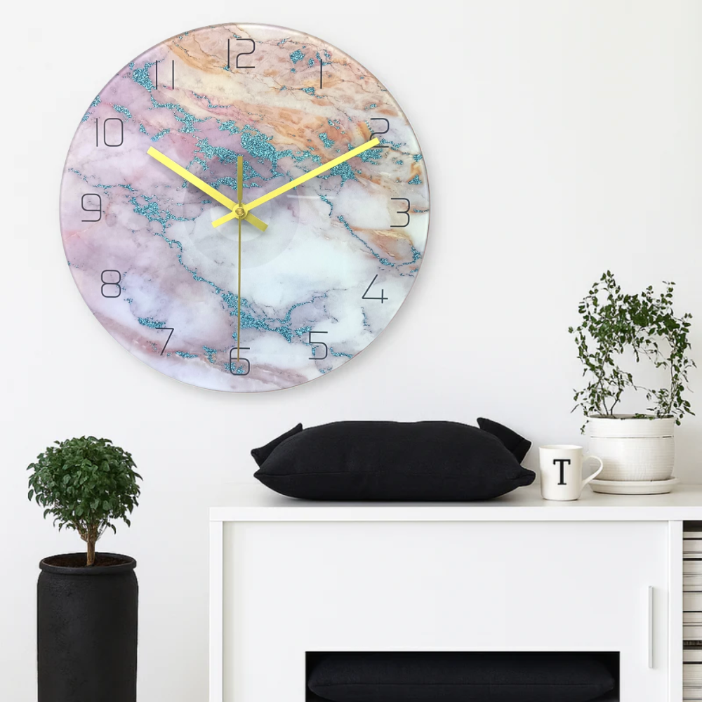Marble-patterned wall clock with gold hands on a white wall above a white cabinet.