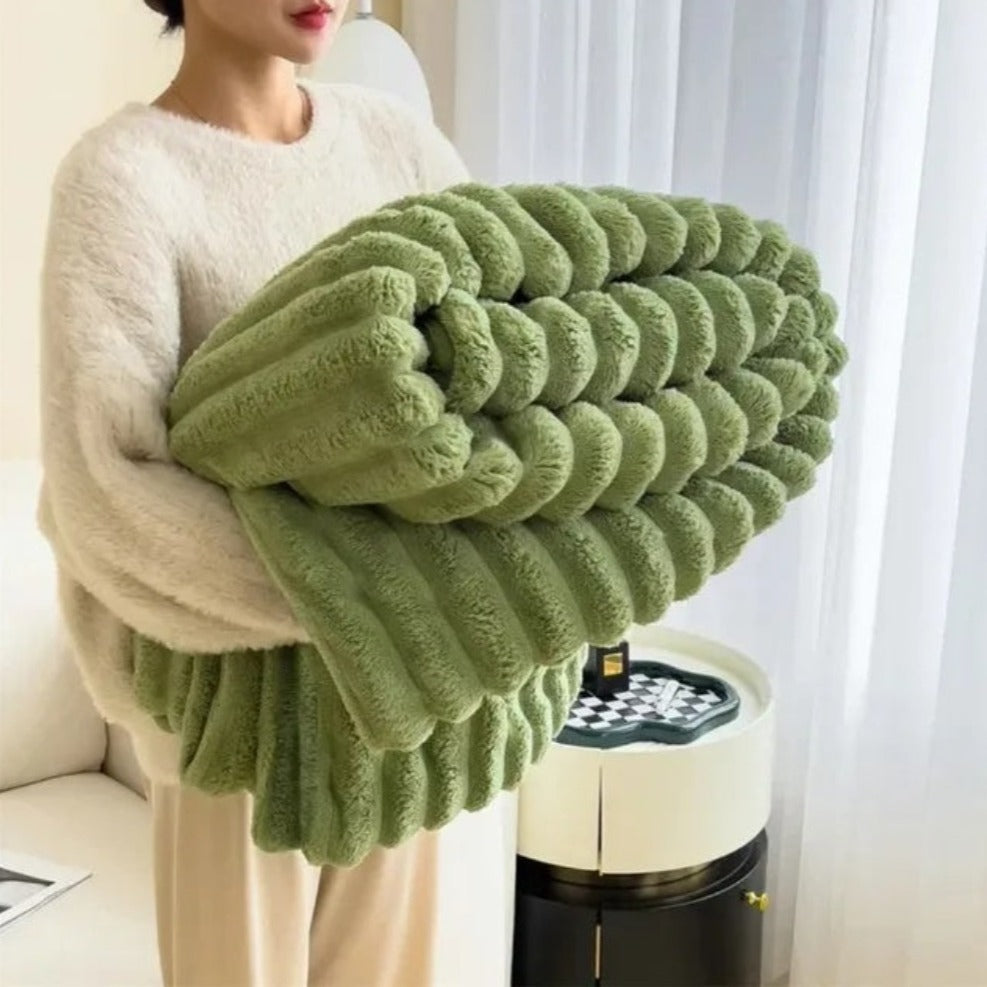 Person holding a large green knitted pillow in a living room setting.