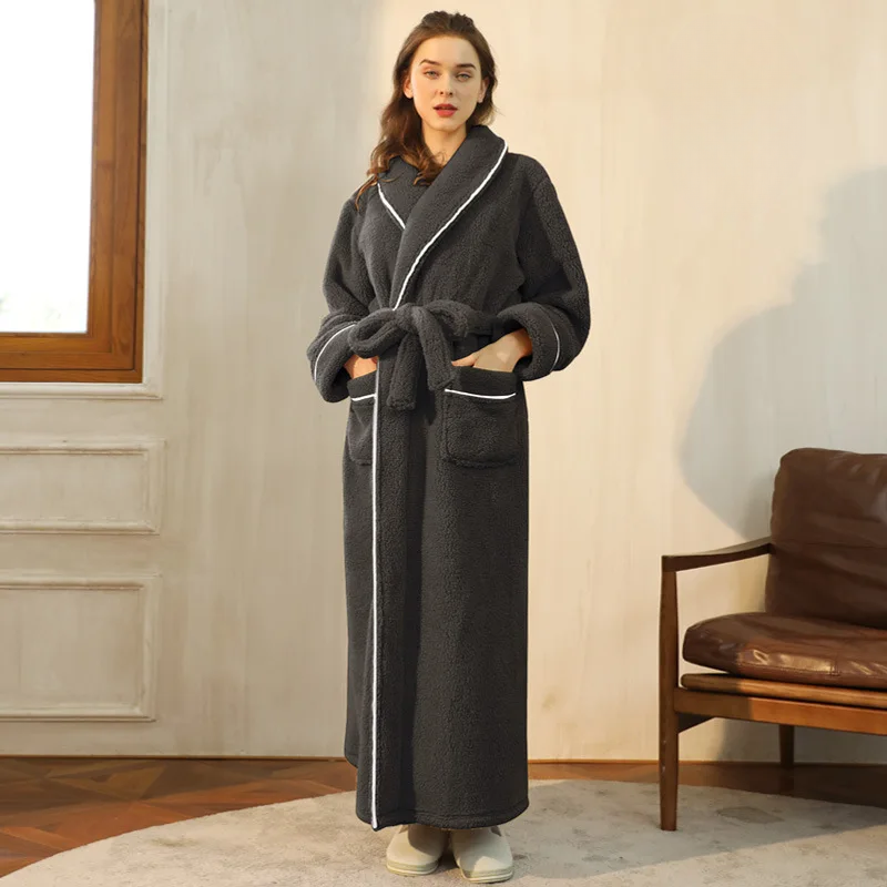 Woman wearing a long dark gray bathrobe in a room with a window and brown chair.