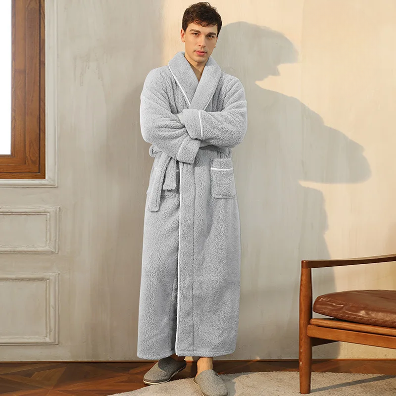 Man wearing a gray bathrobe standing in a room with a wooden chair and neutral walls.