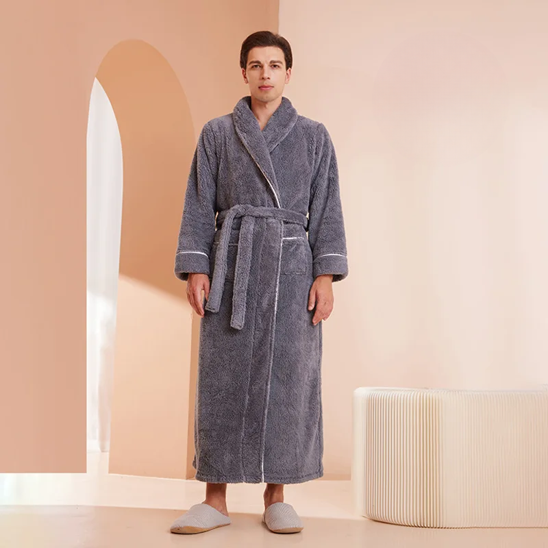 Man wearing a gray bathrobe in a room with a beige wall and white rug.
