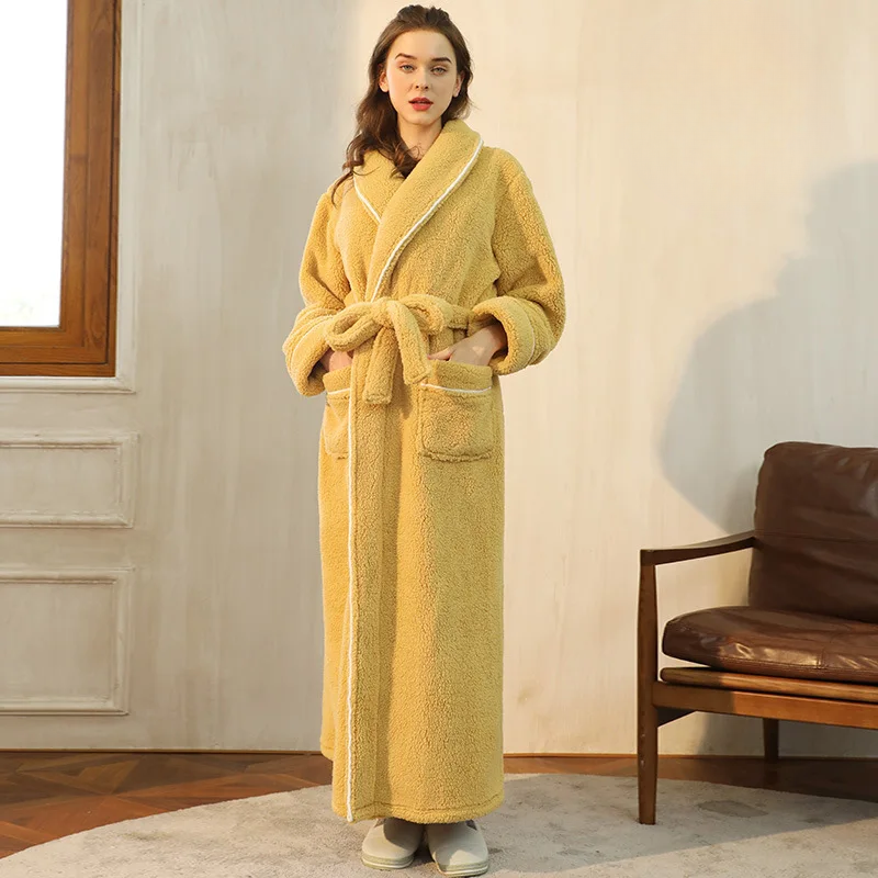 Woman wearing a yellow robe standing in a room with a brown chair and window.