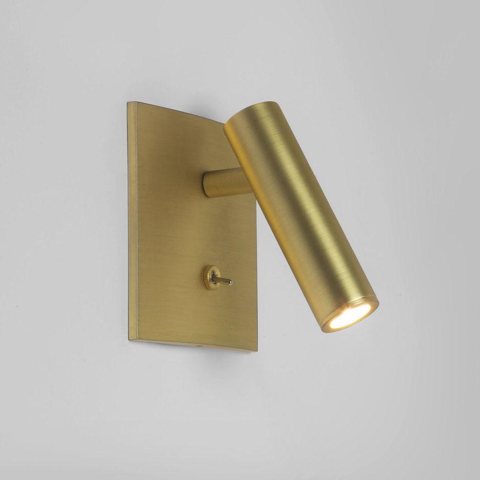 Gold wall-mounted light fixture on a gray background