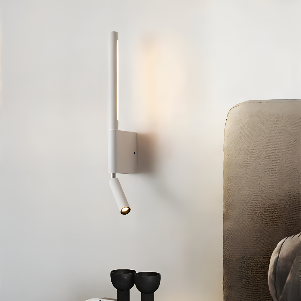 Modern wall-mounted light fixture on a neutral wall with a headboard in the background.