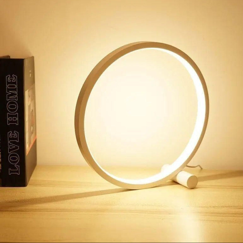 Round LED lamp emitting a warm glow on a wooden surface with a blurred 'LOVE HOME' box in the background.