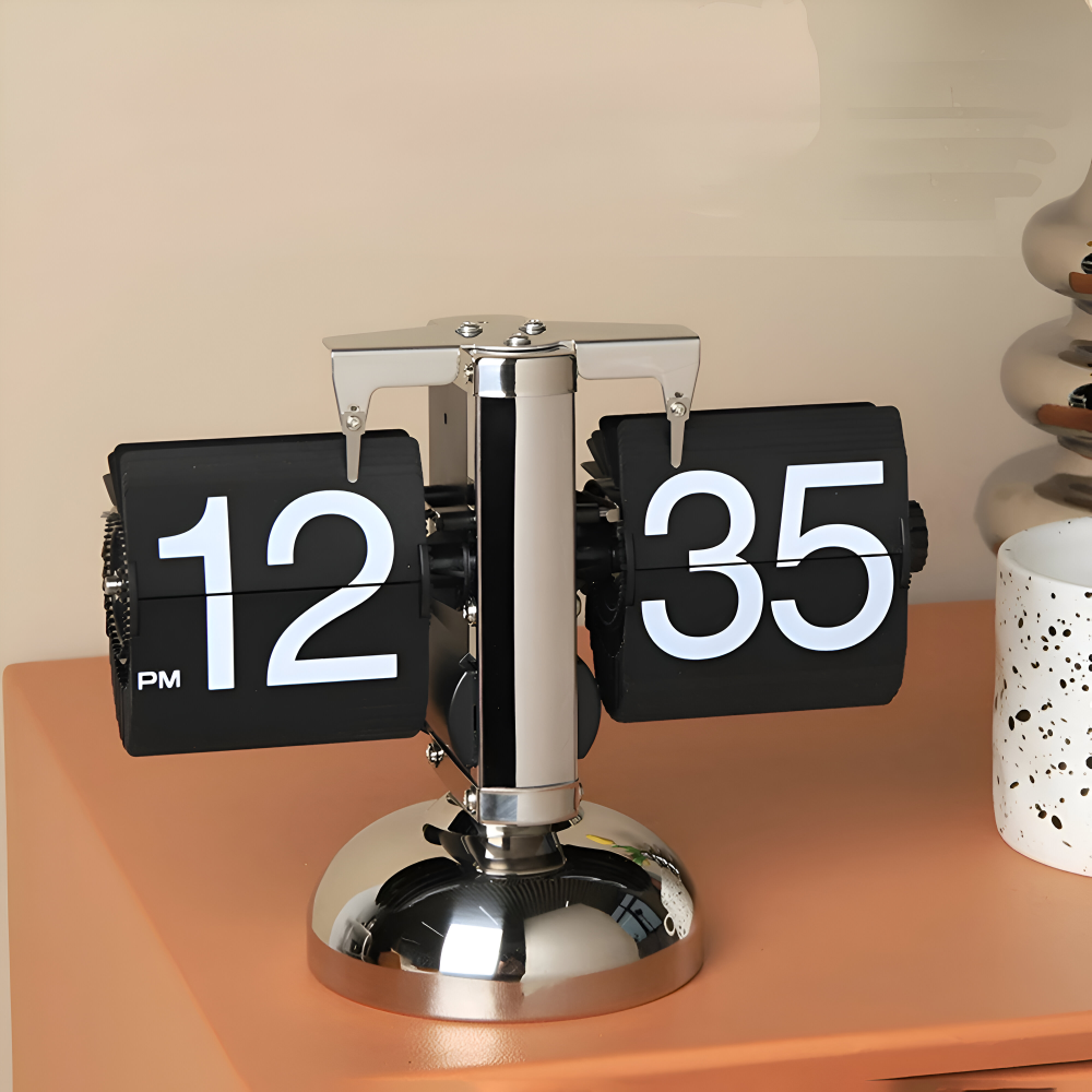 Flip clock with black face and silver base on a wooden surface