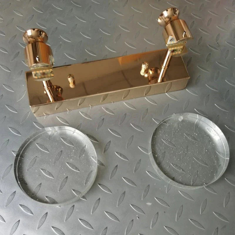 Gold lamp on a metallic surface with two clear circular objects below.